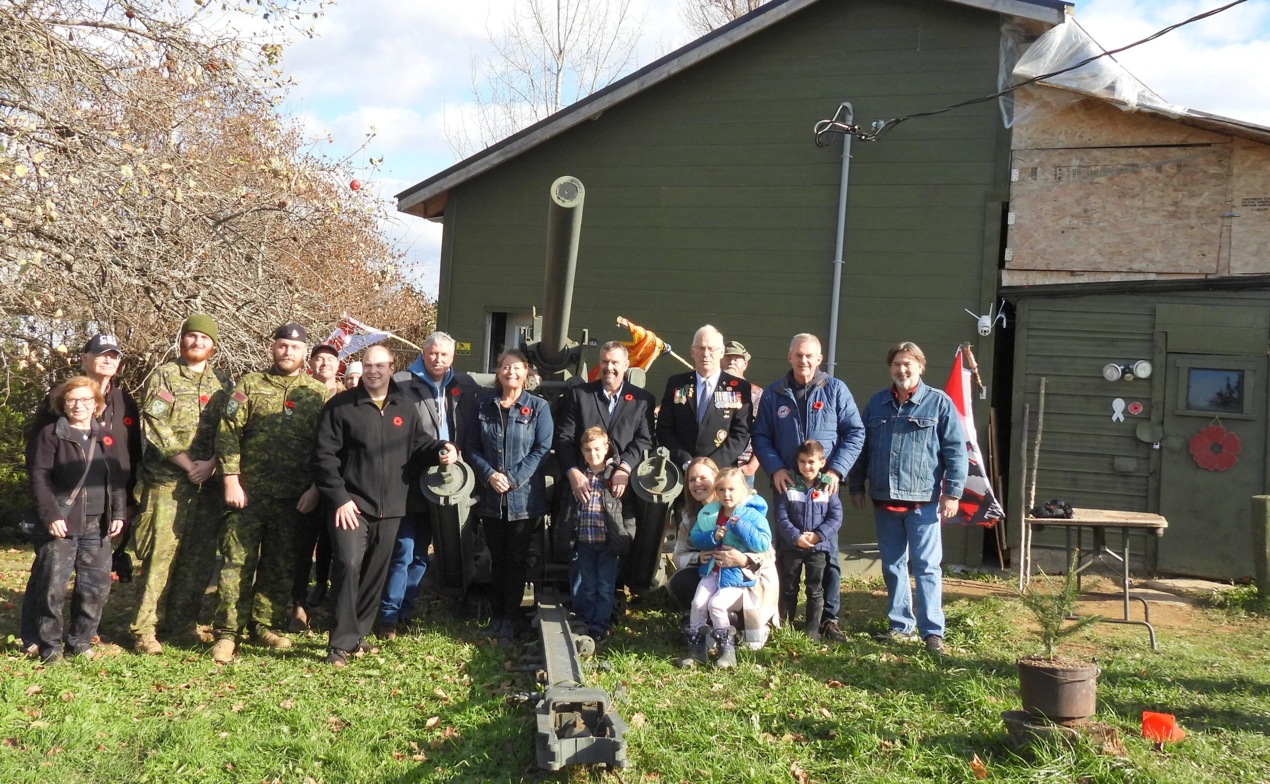 Several visitors join Aaron Bouma (black coat with hand on cannon) at the grand opening of his Carleton County Military Museum in Jacksontown. (Tammey Mclean photo)