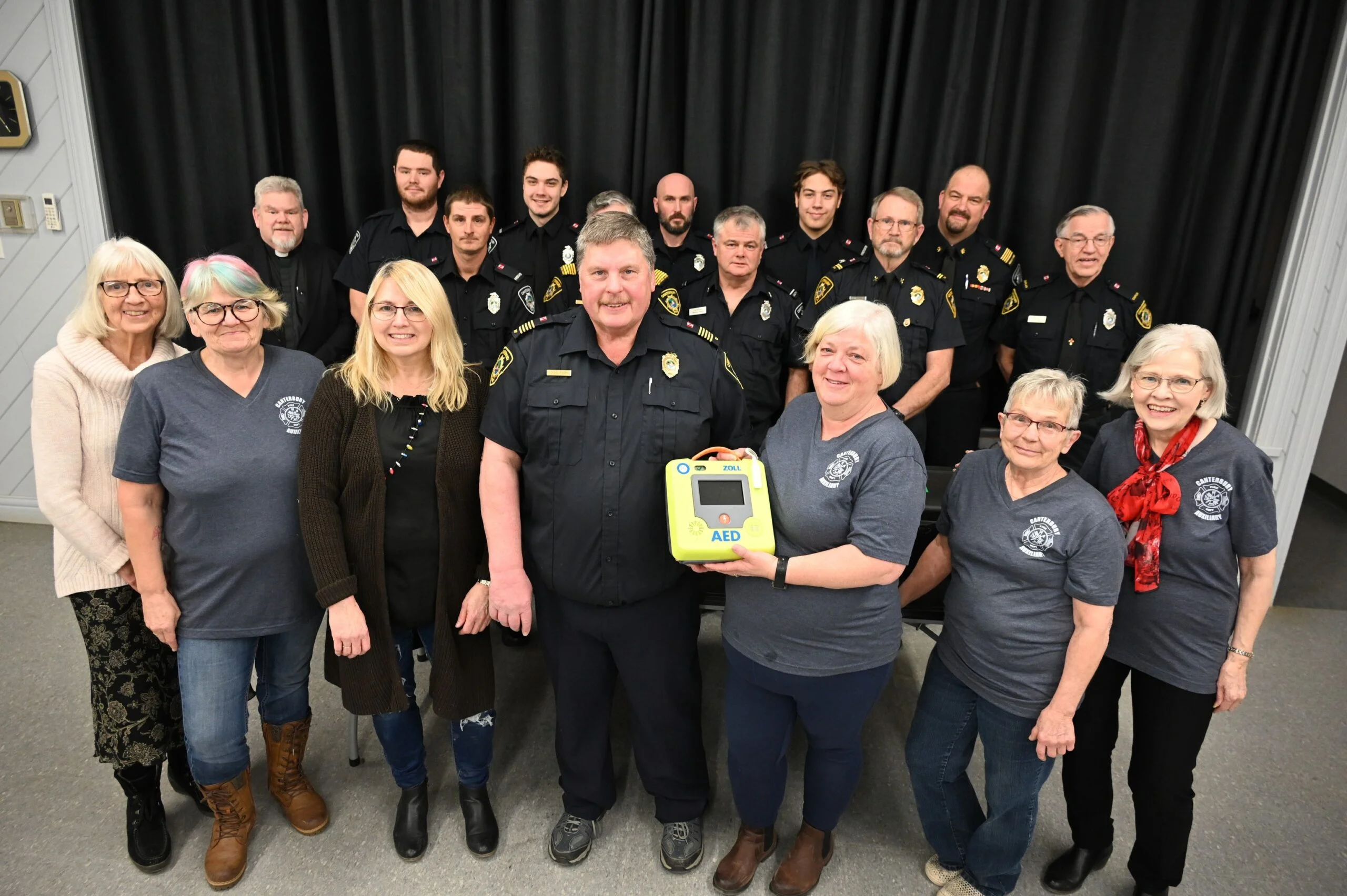 With several members of the Canterbury Fire Department looking on, the department’s Ladies Auxiliary presents Fire Chief Mike Furrow with an AED during a ceremony on Sunday, Feb. 17. From left, Barb Furrow, Secretary Wendy Gauvin, President Heather Neilson-Furrow, Chief Furrow, Vice President Nicole Yerxa, Lisa Anscombe and Treasurer Shirly Yerxa. (Roxana Soetebeer photo)