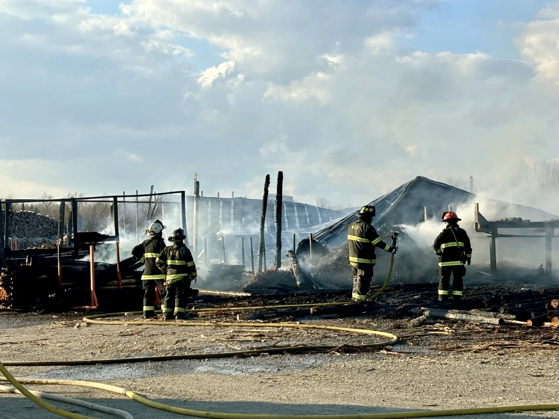 Woodstock and Debec firefighters look over the smouldering remains of a destroyed structure. (Jim Dumville photo)