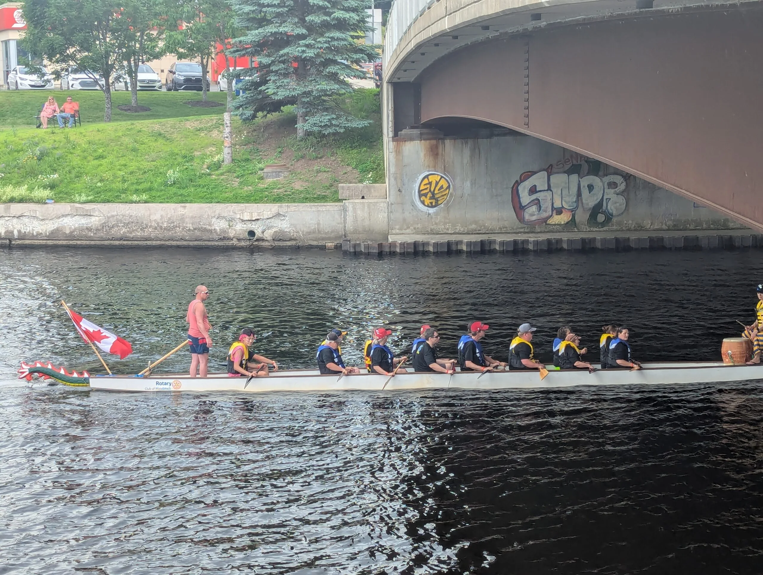 The Woodstock Rotary Club’s Dragon Boat cuts through the Meduxnekeag River during one of its heats during the July 1st Floats event along the Woodstock waterfront in 2025. (Connor Barry photo)